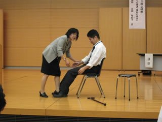 写真：椅子からの離着席の介助を指導する谷岡講師