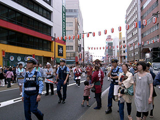 まつりの人混みの中で警察官が警備している様子