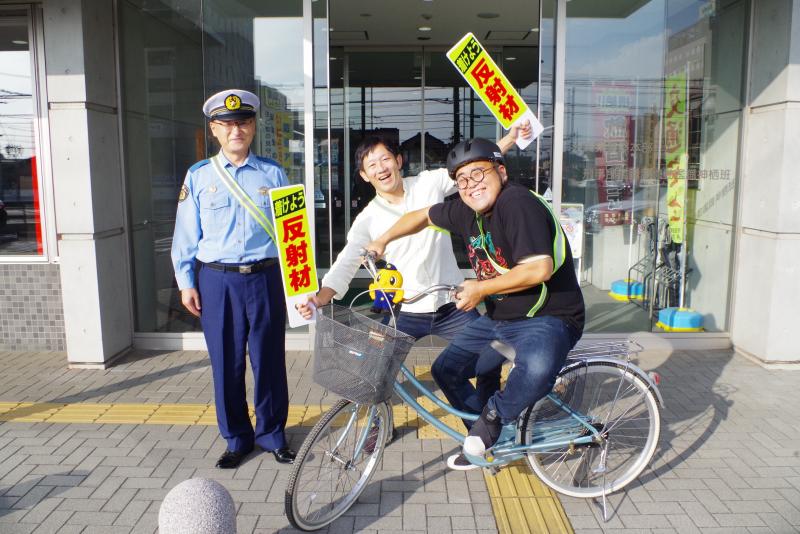 お笑いコンビ「オスペンギン」の二人が神栖警察署の前で警察官と写真撮影。着けよう反射材！着けよう自転車乗車時のヘルメット！